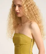 Blusa sin breteles color amarillo mostaza, confeccionada en sarga, con cierre por cremallera invisible en el lateral y bolsillos con solapa en la parte del frente. Posee lastex en la espalda y bajo redondeado.