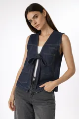 Chaleco de algodón color azul oscuro, con cuello en V, cierre frontal con lazo, bolsillos de parche en el pecho y la cintura, y costuras en contraste.