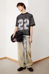 Remera negra de malla con cuello redondo ribeteado y estampado del número 22 en plateado. Corte oversized con hombros caídos y bajo recto.