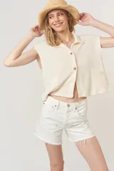 Camiseta color crema de tejido acanalado, corte holgado y cuadrado, con cuello en punta, bolsillos delanteros y cierre frontal con botones.