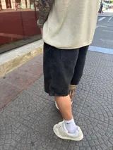 Bermuda de jean negra gastada, corte amplio a la rodilla.