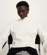 Blusa de punto color blanco, con cuello alto, manga larga y diseño liso.