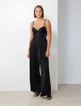 Pantalón palazzo de tiro alto color violeta, de satén. Tiene pretina delantera con pasadores, botón y cierre, pretina trasera elastizada y bolsillos verticales delanteros.