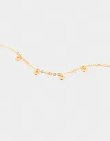 Pulsera dorada flexible con dijes circulares y de circonia cúbica transparente.