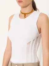 Top blanco de punto con cuello redondo y sisas amplias. Presenta detalle de tres tiras verticales en los laterales.