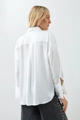 Camisa color crudo de tela satinada con lazos en el escote y mangas largas.