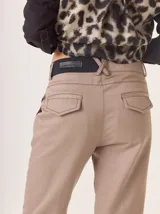 Pantalón de vestir color marrón, corte cigarette (pierna angosta) con tajo en el bajo. Presenta una cintura elástica ancha de color beige claro.