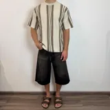 Remera de punto calado color blanco con rayas verticales marrones y negras, corte holgado y mangas cortas.