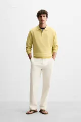Pantalón chino color crema de corte recto, confeccionado en tejido de algodón con elasticidad. Cuenta con bolsillos frontales y traseros de plastrón con botón. Cierre frontal con cremallera y botón.