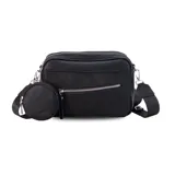 Bandolera negra de cuero sintético con doble bolsillo principal, bolsillo posterior con cierre y bolsillo frontal con detalle de textura diferente. Incluye correa extensible y monedero redondo colgante.