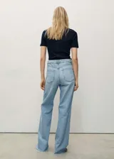Pantalón de jean celeste de corte wide leg, tiro alto, cinco bolsillos, cierre con cremallera y botón, trabillas para cinturón y bajo deshilachado.