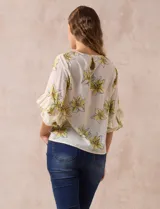 Blusa de gasa color crema con estampado de flores amarillas, de la marca Sioni. Tiene mangas 3/4 con volados y cuello redondo.