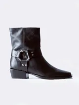 Bota de cuero negra con caña media, puntera ligeramente afilada y detalle de correa con herraje metálico circular y tachas. Taco bajo y ancho.