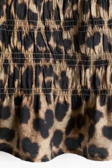 Top sin mangas con estampado animal print, corte ajustado, diseño punto smock, escote bote con volados y peplum.