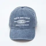 Gorra de gabardina azul con visera curva y ajuste trasero con hebilla metálica. Estampado frontal con la leyenda "Track and Field East Coast Est. 1978 Sports Symposium".