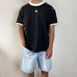 Remera negra de corte regular con cuello redondo y ribetes en contraste color blanco en el cuello y los puños. Presenta un pequeño logo bordado en el pecho.