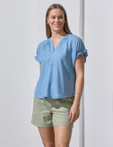 Blusa celeste de lyocell, con cuello a la base y escote en V. Manga corta con detalle de punto smock. Marca Zac & Rachel.