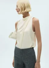 Blusa color crema de tejido fluido satinado, con cuello alto y diseño drapeado.