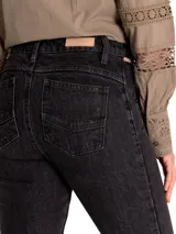 Pantalón de jean negro de tiro medio, corte skinny, con bolsillos delanteros con cierre y ruedo desflecado.