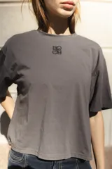 Remera negra de algodón con corte cuadrado, cuello redondo y logo bordado en color naranja.