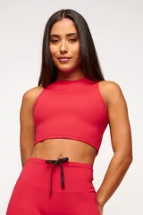 Top deportivo blanco de corte cropped, con cuello alto y logo estampado en el frente.