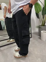 Pantalón cargo negro de corte amplio, con bolsillos laterales con solapa y bolsillos delanteros.