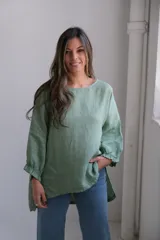 Blusa verde de lino, de corte holgado, con mangas largas con puños elásticos y ruedo asimétrico.