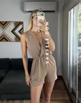 Mono corto negro con escote en V cruzado, sin mangas y con cinturón dorado.