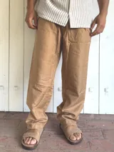 Pantalón de lino color camel, de corte ancho y relajado, con cintura elastizada y cordón ajustable.