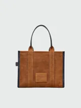 Bolso tote grande Marc Jacobs, modelo The Suede Leather Blocked Large Tote. Cuerpo principal de gamuza color camel con texto en relieve y detalles laterales y base en cuero marrón oscuro.