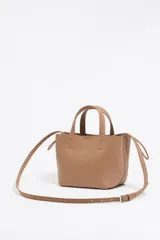 Bolso tote pequeño color visón de piel granulada con doble asa corta y correa bandolera ajustable y extraíble. Incluye bolsa interior ajustable con cordones. Logotipo de la marca grabado en el frente.