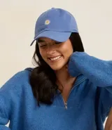 Gorra de sarga color azul con visera curva, ajuste trasero y bordado frontal de una margarita blanca con centro amarillo.