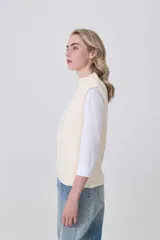 Chaleco de punto color crema, sin mangas, con cuello alto y textura acanalada vertical.