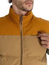 Chaleco inflable color marrón claro con cuello alto y cierre frontal con cremallera. Tiene dos bolsillos laterales y un bolsillo en el pecho con cierre.