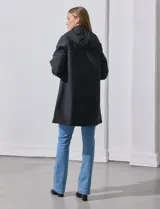 Gabardina impermeable negra, marca Weatherproof, con cierre central oculto y botones a presión. Tiene bolsillos delanteros con cierre, capucha no desmontable y forro interno de abrigo desmontable.