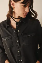 Camisa de manga larga confeccionada en tencel azul denim, de corte clásico, con cuello camisero, bolsillos en el frente y botones metálicos.