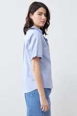 Camisa celeste de manga corta con cuello y ruedo con volados.