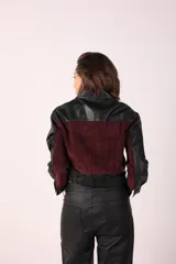Campera corta de cuero sintético negra con detalles en gamuza color borgoña en la parte superior del pecho y bolsillos con cierre.
