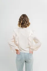 Blusa color crema con volados en el frente, detalle de puntilla y bordados florales en mangas.