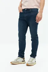 Jean slim azul oscuro, tiro medio, con pasacintos y confeccionado en 98% algodón y 2% spandex.