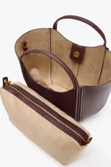 Bolso mini city color borgoña, con asa de mano y asa bandolera extraíble. Tiene detalle de pespuntes en contraste y bolsa interior extraíble con cierre de cremallera.