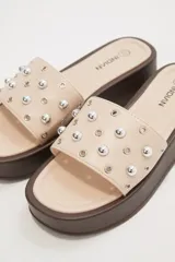 Sandalias color beige con plataforma marrón y apliques de tachas plateadas.