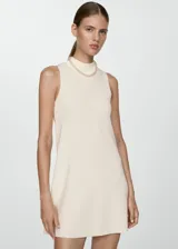 Vestido corto evasé color crudo, de tejido de punto fino, sin mangas y con cuello perkins.