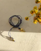 Collar con dije de caracola dorada y cordón fino azul.