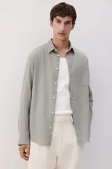 Camisa manga larga color verde oliva, de corte recto, con cuello inglés, tapeta clásica, canesú en la espalda, bolsillo superior abierto, cierre ajustable de botón en los puños y bajo redondeado.