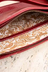 Cartera de cuero vegano con textura de serpiente, color rojo, con correa de cadena y strap ajustable.