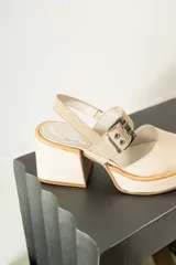 Zapato de cuero color beige con punta redondeada, taco cuadrado y correa con hebilla.