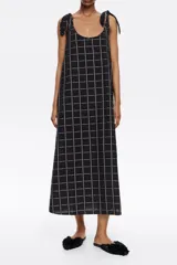Vestido midi negro con estampado a cuadros blancos, corte recto, escote redondo y tirantes con lazos.