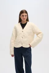 Campera color crema con diseño matelaseado y bordado floral, de corte recto y manga larga.