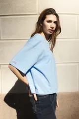 Remera blanca de algodón con cuello redondo y mangas cortas. Presenta un bordado del sol de la bandera uruguaya en el pecho.
